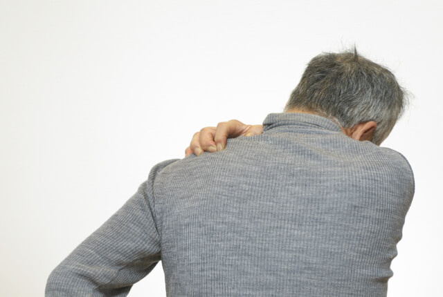 片手で肩を抑える男性